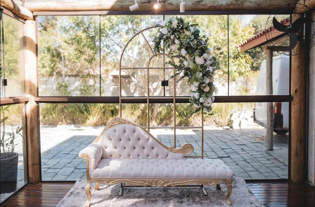 Chaise clássica com arco floral dourado ao ar livre